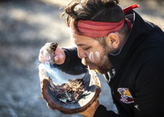 Aboriginal guide Dwayne Bannon-Harrison performing a smoking ceremony during a traditional welcome on a Ngaran Ngaran Culture Awareness tour