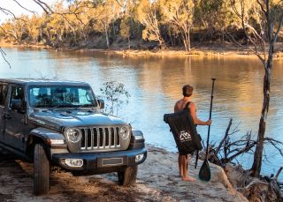 Man preparing for an afternoon of stand up paddleboarding on the Murray River, Echuca-Moama