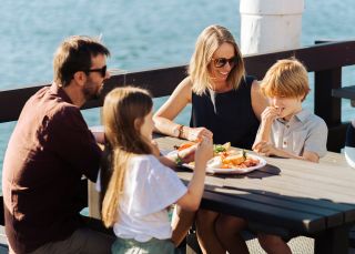 Family enjoying fresh seafood on the water at Wallis Lake Fishermen's Co-Op, Tuncurry