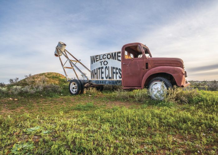A red truck with a sign welcoming visitors to White Cliffs in Outback NSW