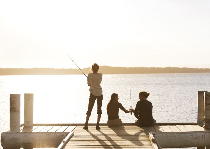 Friends fishing off the jetty at Raffertys Resort in Lake Macquarie, North Coast