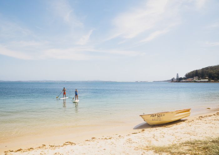 Couple enjoying a stand up paddleboarding experience in Shoal Bay, Port Stephens