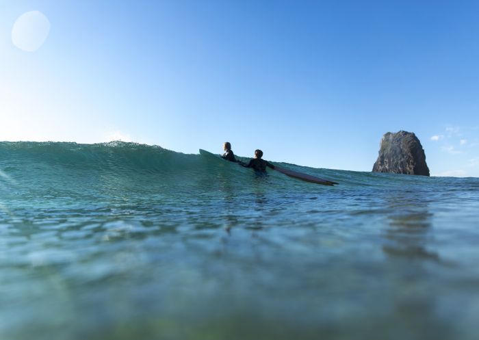 Father and son enjoying a morning surf at Glasshouse Rocks, Narooma in Batemans Bay, South Coast