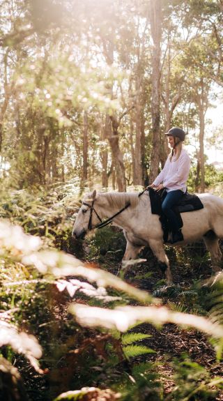 Woman enjoying a horse-riding experience near Tyagarah Beach with Zephryr Horses in Byron Bay