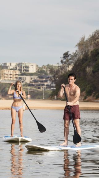 Couple enjoying a day of stand up paddleboarding on Terrigal Lagoon, Terrigal in Gosford Area