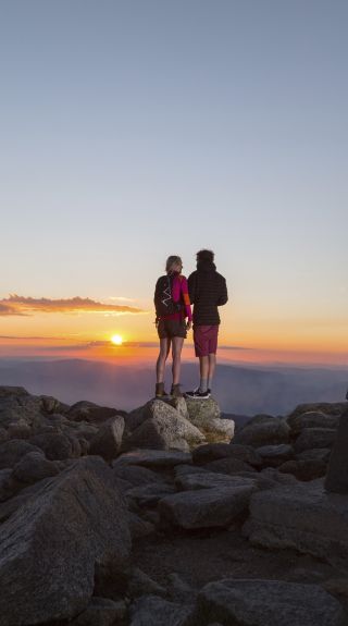 Couple watching the sun set at the summit of Mount Kosciuszko in Kosciuszko National Park