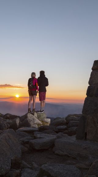 Couple watching the sun set at the summit of Mount Kosciuszko in Kosciuszko National Park