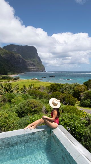 Woman relaxing by the pool at Capella Lodge, Lord Howe Island