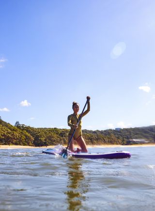 Woman enjoying a morning of stand up paddleboarding at Pearl Beach on the Central Coast