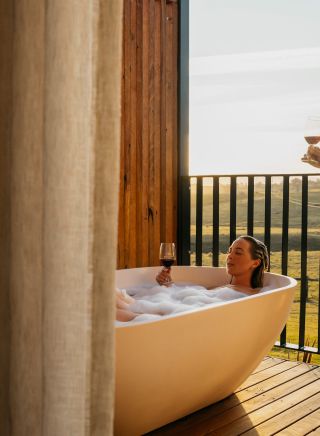 Couple enjoying bath and wine from balcony at Cupitt's Estate Villas, Ulladulla