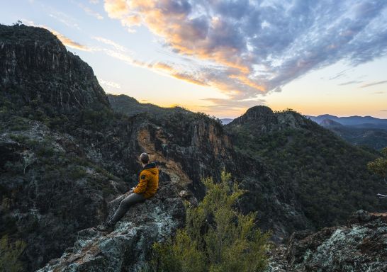 Hiker watching sunset over volcanic rock formations, Warrumbungle National Park